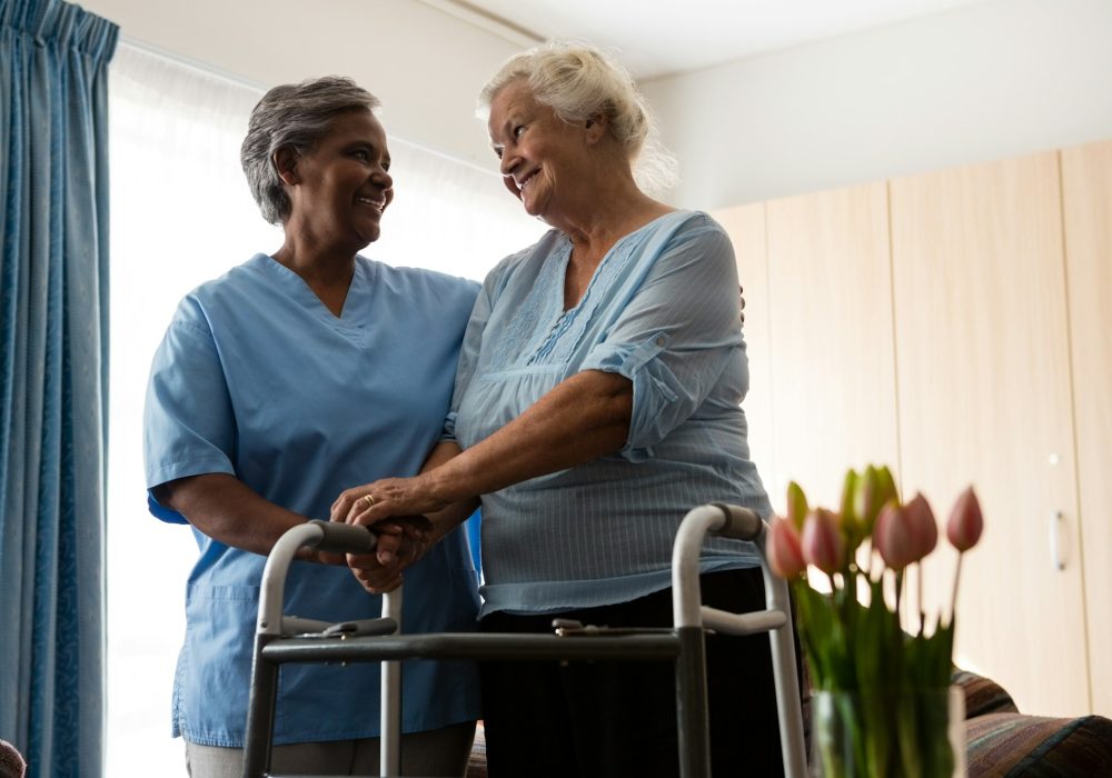 Nurse assisting senior patient in walking with walker